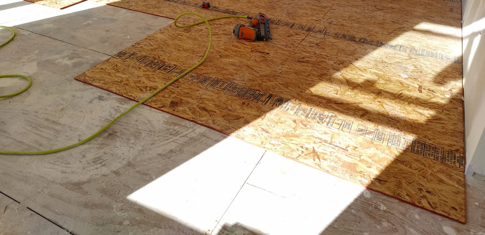 New OSB subfloor panels being nailed down over an existing plywood subfloor by Forever Flooring
